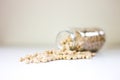 Jar of non-perishable dried chick peas spilled on a white table - preserved for Covid-19