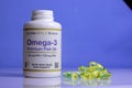 A jar of omega 3 vitamins, vitamins are on the table, a wooden spoon with omega 3 vitamins on a blue background, the concept of a