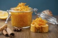 A jar of orange confiture with piece of French baguette, cinnamon and star anise on the wooden background