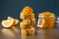 A jar of orange confiture and pieces of French baguette with star anise and red flowers on the sackcloth and wooden background