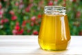 Jar of organic floral honey with a drizzle against flowers background . Outdoor