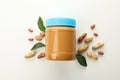 Jar with peanut butter, peanuts and leaves on white background Royalty Free Stock Photo