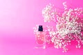 A jar of perfume on a pink background with gypsophila