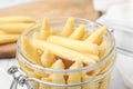 Jar of pickled baby corn on white table, closeup