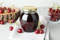 Jar of pickled cherries and fresh fruits on light table Royalty Free Stock Photo