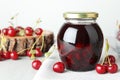 Jar of pickled cherries and fresh fruits on light table, closeup Royalty Free Stock Photo