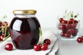 Jar of pickled cherries and fresh fruits on light table, closeup Royalty Free Stock Photo