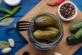 Jar of pickled cucumbers and ingredients for food preservation on blue wooden table, top view