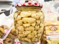 Jar of pickled garlic cloves with herbs in grocery store setting Royalty Free Stock Photo