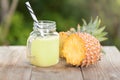 A jar of pineapple juice with a raw pine apple