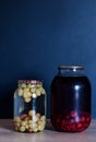 Jar of raspberry, cherry and grape juice on the wooden table in front of black wall Royalty Free Stock Photo