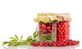 Jar with rose hips and Rowan berries, next to sprig and scattered fruit, isolated on white Royalty Free Stock Photo