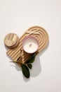 A jar of scented candles is placed on a domed wooden platform with cotton swabs and green leaves on a white background. Enjoy Royalty Free Stock Photo