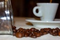 Jar with spilled coffee beans on linen tablecloth with cup of espresso full with spoon Royalty Free Stock Photo