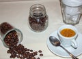 Jar with spilled coffee beans on linen tablecloth with cup of espresso full with spoon Royalty Free Stock Photo