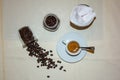 Jar with spilled coffee beans on linen tablecloth with cup of espresso full with spoon. Royalty Free Stock Photo