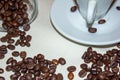 Jar with spilled coffee beans on linen tablecloth with cup of espresso full with spoon Royalty Free Stock Photo