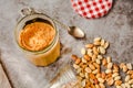 Jar and spoon of peanut butter and peanuts on dark wooden background from top view. Close-up Royalty Free Stock Photo