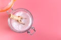 Jar and spoonful of baking soda on pink background. Royalty Free Stock Photo