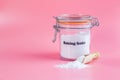 Jar and spoonful of baking soda on pink background Royalty Free Stock Photo