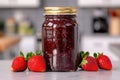 A jar of strawberry jam with fresh strawberries near the jar stands on the kitchen table Royalty Free Stock Photo