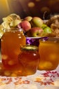 a jar of sweet honey on a table from the garden with apples in a glass jar with cheese and roses and fresh bread with