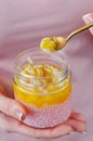 Jar of tapioca and pineapple jam. A woman is eating a healthy dessert from a jar with a teaspoon