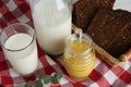 Jar with tasty honey, milk and bread on checkered cloth, above view Royalty Free Stock Photo