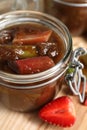 Jar of tasty rhubarb jam and strawberry on wooden table, closeup Royalty Free Stock Photo