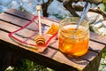 A jar of thick golden honey with a spoon, a wooden honey dipper in a glass plate and a piece of honeycomb. Harvesting