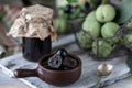 Jar of walnut jam on a wooden table and a group of green walnuts