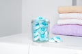 Jar with water softener tablets near stacked towels on washing machine Royalty Free Stock Photo