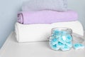 Jar with water softener tablets near stacked towels on white table Royalty Free Stock Photo