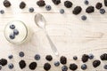 Jar of yogurt with blueberries, teaspoon, blackberries and blueberries on the edges.