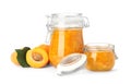 Jars of apricot jam and fresh fruits on background