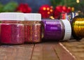 Jars, bottles full of shiny rhinestones, sparkles, confetti on wooden background