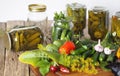 Jars of cucumbers and ingredients for pickling on a wooden kitchen board.The process of preserving cucumbers in glass jars under