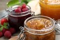 Jars with different jams and fresh berries on wooden table, closeup Royalty Free Stock Photo