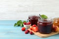 Jars with different jams and fresh fruits on light blue wooden table. Space for text Royalty Free Stock Photo