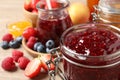 Jars with different jams and fresh fruits on table, closeup. Space for text Royalty Free Stock Photo