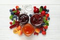 Jars with different jams and fresh fruits on white wooden table, flat lay Royalty Free Stock Photo