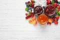 Jars with different jams and fresh fruits on white wooden table, flat lay. Space for text Royalty Free Stock Photo