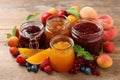 Jars with different jams and fresh fruits on wooden table Royalty Free Stock Photo