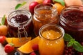 Jars with different jams and fresh fruits on wooden table, closeup Royalty Free Stock Photo
