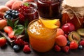 Jars with different jams and fresh fruits on wooden table, closeup Royalty Free Stock Photo