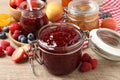 Jars with different jams and fresh fruits on wooden table, closeup Royalty Free Stock Photo