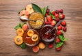 Jars with different jams and fresh fruits on wooden table, flat lay Royalty Free Stock Photo
