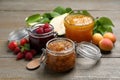 Jars with different jams and fresh fruits on wooden table Royalty Free Stock Photo