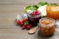 Jars with different jams and fresh fruits on wooden table. Space for text Royalty Free Stock Photo