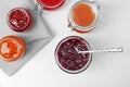 Jars with different sweet jam on table